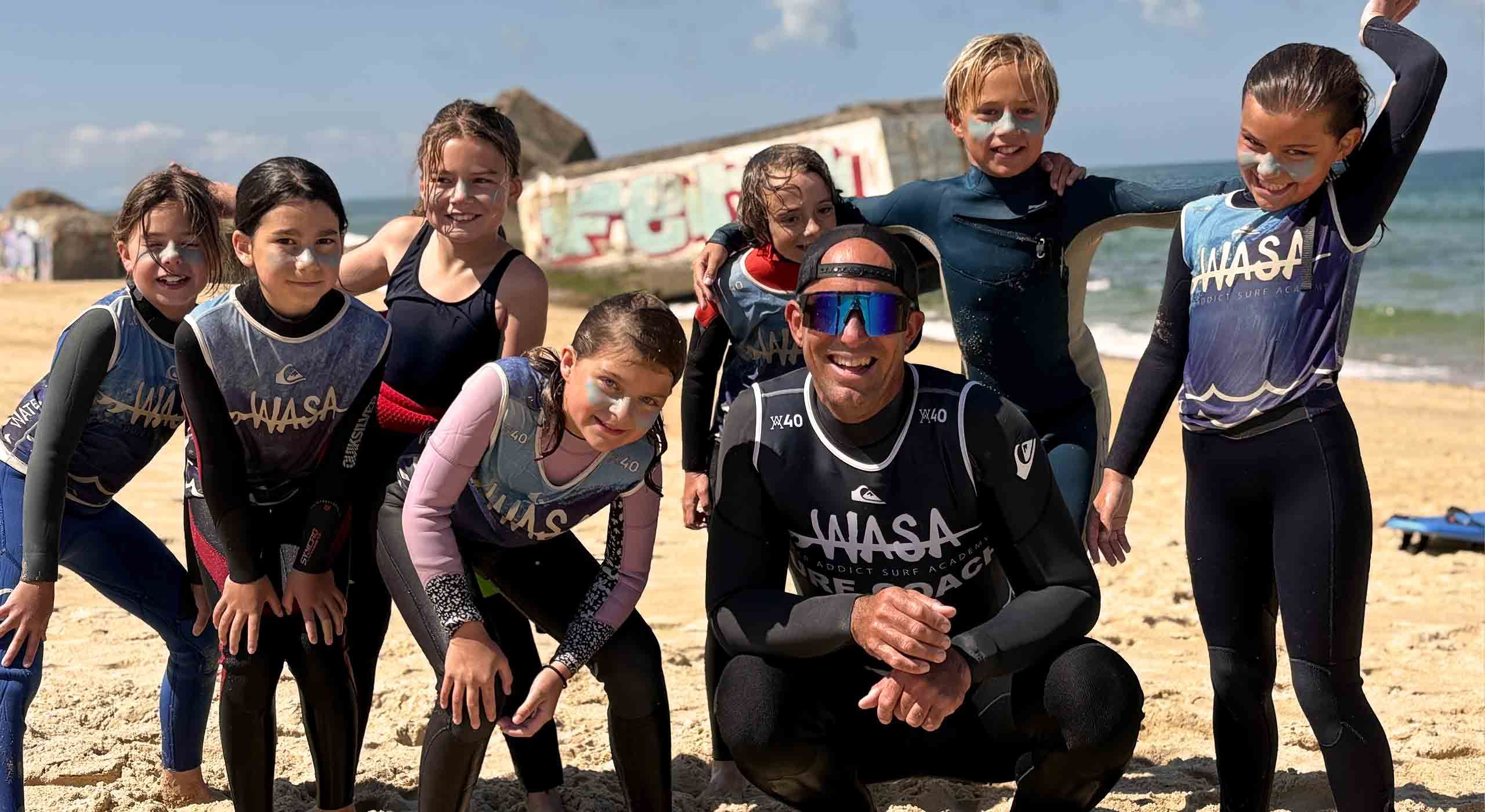 groupe d'enfants avec Franck le coach posant sur la plage après un cours de surf enfant à capbreton