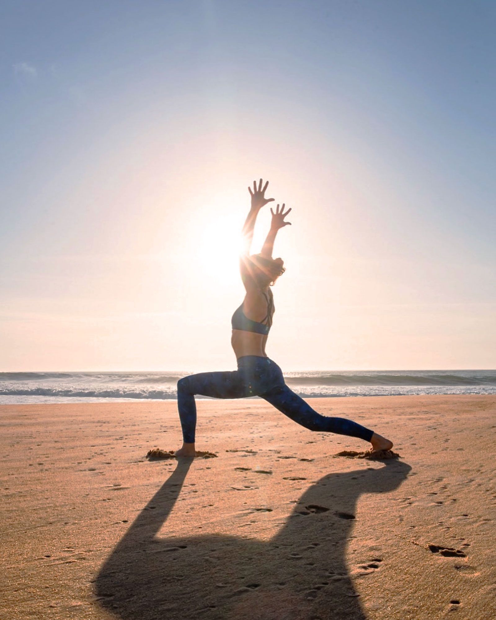 prof de yoga posant sur la plage les bras en l'aire pour échauffement d'un cours de surf à capbreton