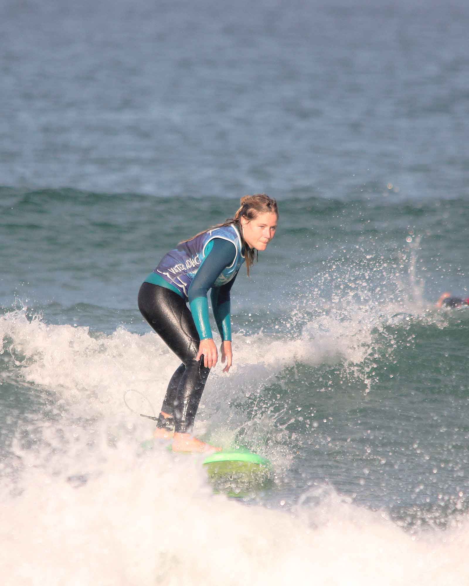 jeune femme avec lycra bleu du club de surf capbreton wasa surfant une petite vague